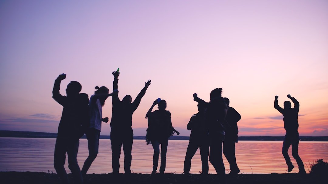 Group of young dancing people have a party at beach on sunset